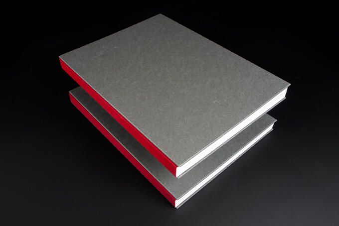 Steifbroschur mit rotem Leinenband und Prägung auf Titel