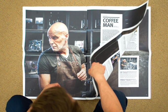 Druckobjekt im Überformat vor dem ein Mann sitzt